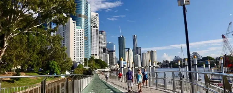 Brisbane látnivalók ikonikus folyóparti sétánya a Kangaroo Point Cliffs alatt, háttérben a Story Bridge és a CBD felhőkarcolói. A város élhetőségét meghatározó vízparti életérzés egyetlen képkockában.