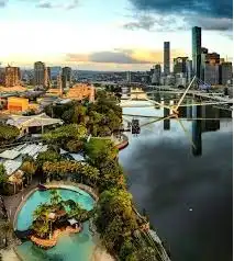 A brisbane-i South Bank panorámája a Streets Beach lagúnával, a Brisbane Riverrel és a város felhőkarcolóival napfényes, élhető folyóparti környezetben.