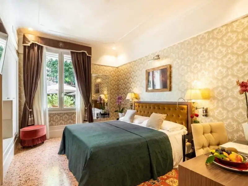 Hotel Moresco világos, arany mintás falú szoba kilátással és piros puffal