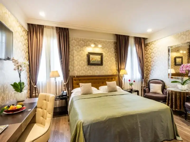 Tágas Hotel Moresco szoba zöld ágytakaróval és két fotellel Velencében
